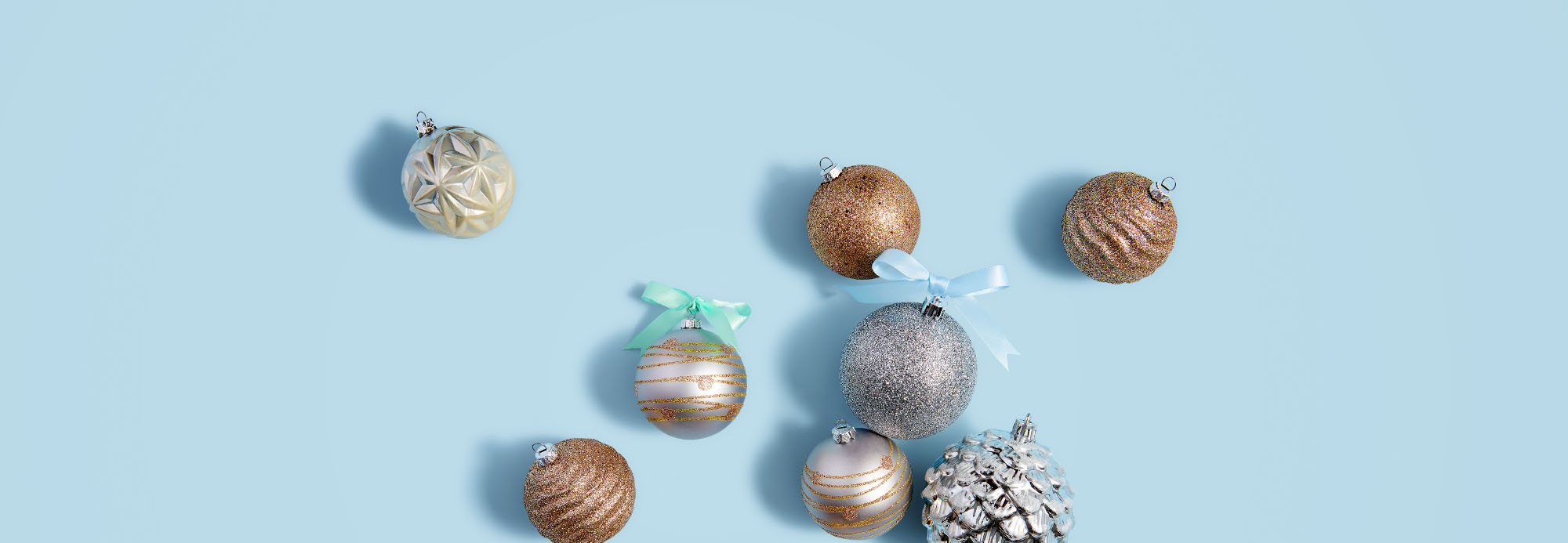 Shiny holiday ornaments on a light blue background